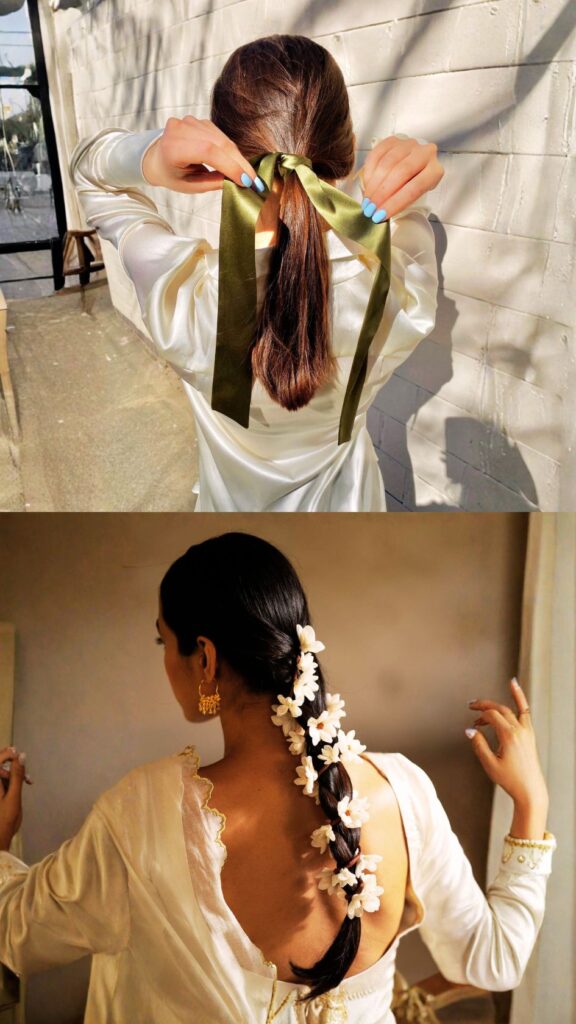 A vertical collage showcasing two ways to elevate a simple hairstyle with accessories. The top image shows a woman with smooth, medium-brown hair tying a long, olive-green satin ribbon around a low ponytail. The bottom image features a woman with dark hair in a long, sleek braid that has been intricately decorated with a cascade of small, fresh white jasmine flowers. Both images emphasize how textiles and florals can transform a basic style into a formal masterpiece.