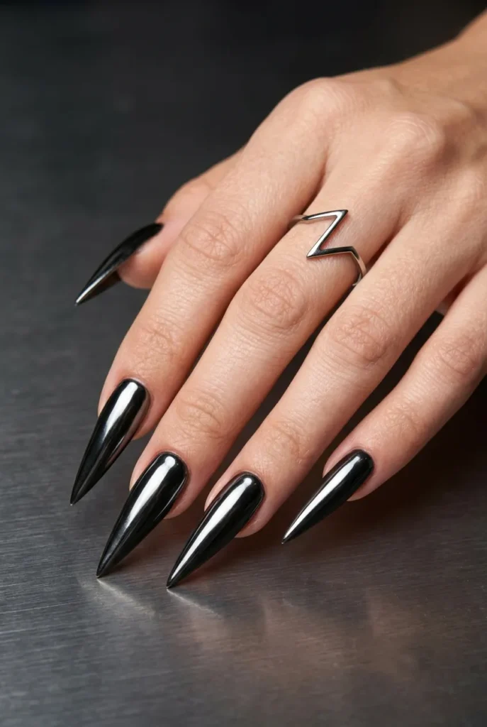 A macro photo of extremely long, razor-sharp 'saber' nails painted with a mirror-like black chrome finish against a dark metallic background.
